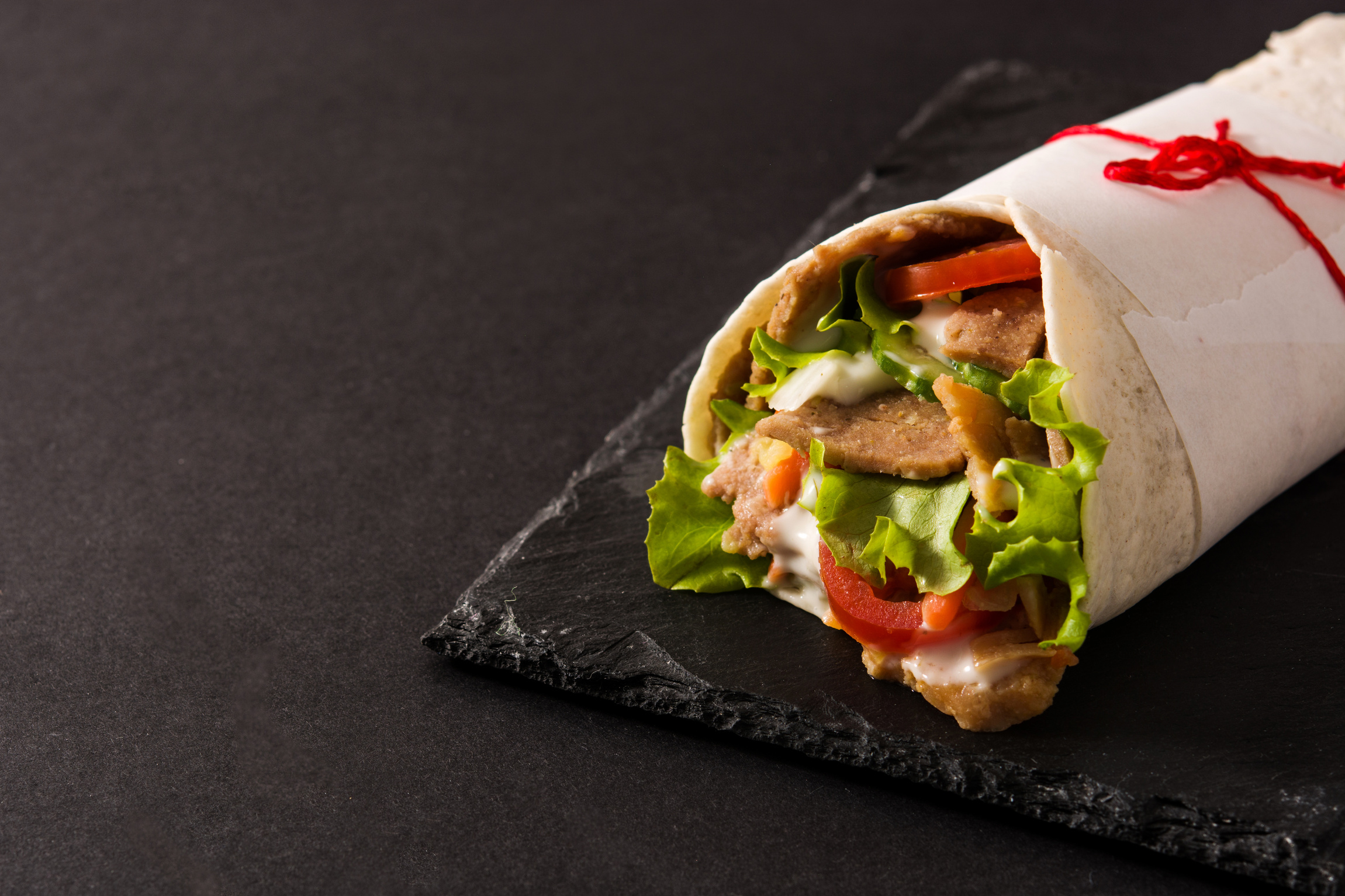 Doner kebab or shawarma sandwich on wooden table. 	